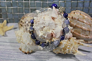 Bracelet made of natural stones on the background of sea shells.