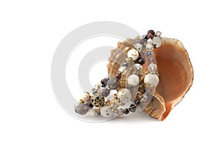 Bracelet made of natural stones on a sea shell on a white background