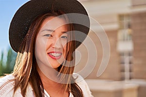 Braces on the teeth, a girl of Asian appearance in a white T-shirt and a dark hat, looking at the camera and smiling