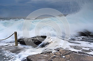 Bracing as powerful waves come crashing over rocks