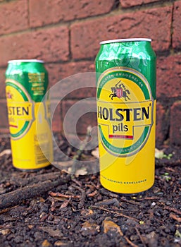 Discarded empty Holsten Pils Beer Cans by a brick wall