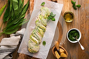 Braided wild garlic pesto brioche. Homemade fresh pull apart bread with wild garlic pesto on wooden board on wooden background