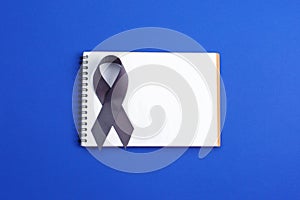 Brain cancer grey color awareness ribbon isolated on blue background photo