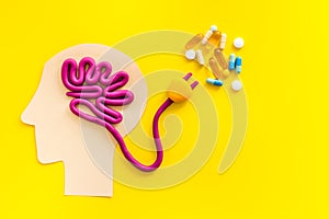 Brain charging and mental rest. Plug and cable leads to plastiline meanders on yellow background