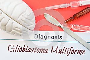 Brain figure, surgical scalpel, syringe and vials lying around title Diagnosis Glioblastoma Multiforme. Concept photo for diagnosi