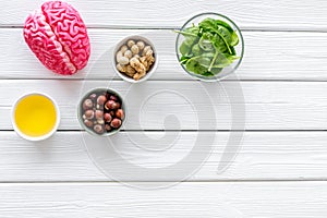Brain food concept with peanut, hazelnut, seed-oil, spinage on white wooden background top view copyspace