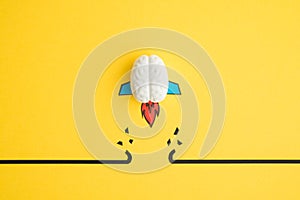 Brain rocket breaking through black wall obstacle on yellow background minimal style. Concept of breakthrough for new idea