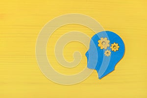 Brain works concept. Thinking, creativity concept of the human head with gears on yellow background