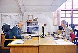 The brains behind the business. a two people working at their desk in the office of a warehouse.