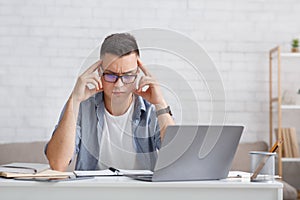 Brainstorm and find solution. Concentrated guy thinks difficult task, sitting at table with laptop