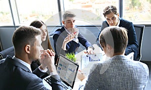 Brainstorm. Group of business people looking at the laptop together. One business woman looking at camera.