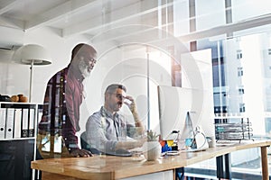 Brainstorming alternatives. two businesspeople working on a computer in an office.