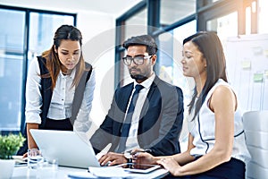 Brainstorming is crucial for business. a group of young businesspeople using a laptop together in a modern office.