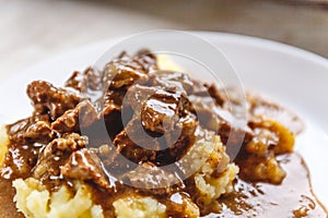 Braised beef, beef stroganoff with gravy on mashed potatoes. Close-up, top view