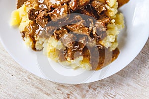 Braised beef, beef stroganoff with gravy on mashed potatoes. Close-up, top view