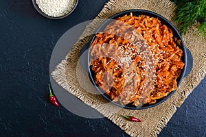 Braised cabbage from tomato sauce in a cast-iron frying pan on a black background. Lenten menu. Diet low-calorie vegetable dish.