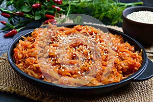 Braised cabbage from tomato sauce in a cast-iron frying pan on a black background. Lenten menu. Diet low-calorie vegetable dish