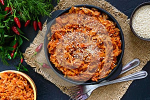 Braised cabbage from tomato sauce in a cast-iron frying pan on a black background. Lenten menu. Diet low-calorie vegetable dish.