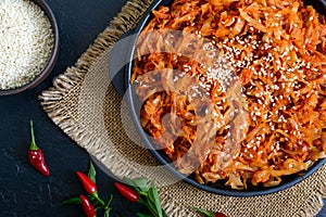 Braised cabbage from tomato sauce in a cast-iron frying pan on a black background. Lenten menu. Diet low-calorie vegetable dish.