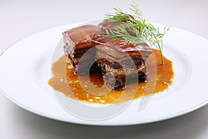 Braised pork meat in Chinese style with herbs on white plate photo
