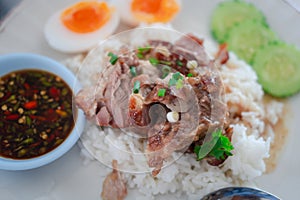 Braised pork placed on hot steamed rice served with boiled egg and sliced cucumber