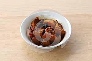 Braised pork with sweet soy sauce aka "babi kecap" served on a bowl in wooden table