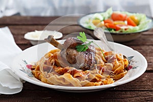 Braised Rabbit Leg in Tomato Sauce with Homemade pasta, dark rustic background