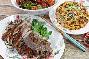 Braised sliced pork trotters, with mapo doufu and fragrant spicy mini lobsters in background. Asian Chinese food on table concept