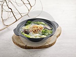 Braised Vegetable and Conpoy with Vermicelli in Fish Soup served in Casserole served in a dish isolated on wooden board side view