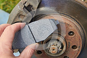 brake pad in the hands of a car mechanic,on the background of a car brake disc in the hands of the front brake pads