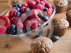 Bran muffins and berry fruit on wooden board