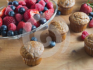 Bran muffins and berry fruit on wooden board