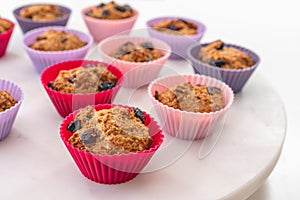 Bran muffins with dry cranberries close up in baking silicon cups on white background.