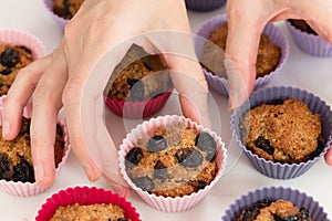 Bran muffins with dry cranberries close up in baking silicon cups on white background.