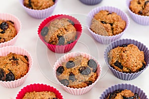 Bran muffins with dry cranberries close up in baking silicon cups on white background.