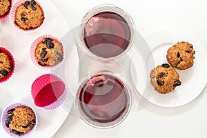 Bran muffins with dry cranberries, and cups of hibiscus tea close up on white background.