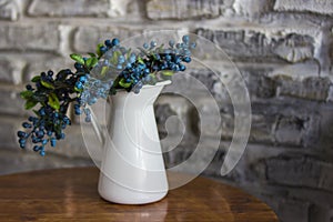 A branch of blueberries with berries in a blue vase close up. Blueberry in a white vase. White vases and blueberries. A bush of bl