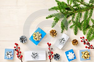 A branch of a Christmas tree, blue and white gift boxes, cones and red berries. Christmas composition with a copy space