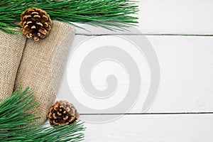 Branch christmas tree and cone on burlap on white wooden vintage background
