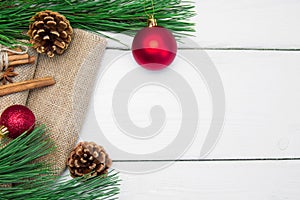 Branch christmas tree and red ball with cinnamon on burlap on white wooden vintage background