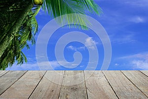 Branch of Coconut trees and old wooden foreground with blue sky and clouds background, empty space Place a product