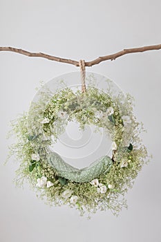 On the branch hangs a ring cradle for a photo shoot of newborns, a dream catcher, a floral arrangement with eustomas