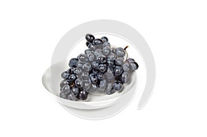 Branch of ripe blue grape on plate isolated white background