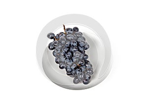 Branch of ripe blue grape on plate isolated white background