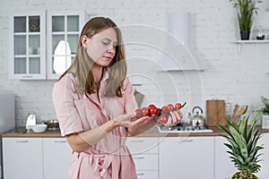 A branch of ripe cherry tomato in the hands of a young girl