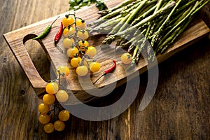 branch with yellow cherry tomatoes, asparagus, hot peppers and Brussels sprouts