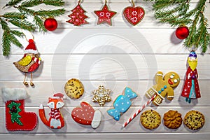 Branches of a Christmas tree, New Year`s decor, gingerbread and cookies on a light wooden background. Macro, horizontal photo.