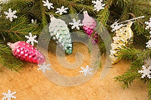 The branches of Christmas trees and fallal cone decorations on the background of wooden boards and snowflakes.