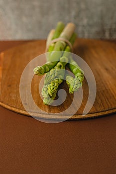 branches of fresh green asparagus on a wooden board, brown background, top view. Basic trend concept with copy space.