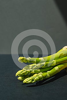branches of fresh green asparagus on a wooden board, dark gray background, top view. Basic trend concept with copy space